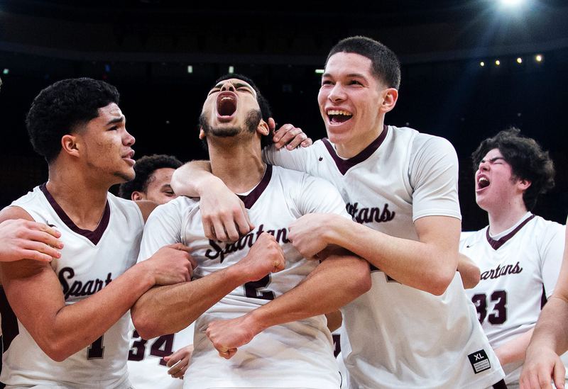 Basketball teammates wrap up a shouting teammate after a big play